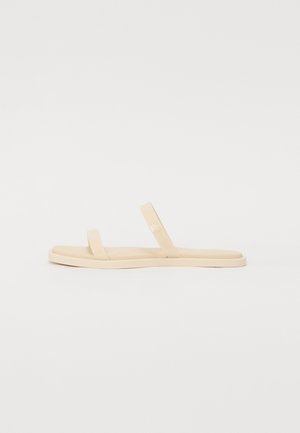 Beige flip-flop sandals with minimalistic design, featuring two thin straps and a flat sole. Made of smooth synthetic material.