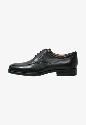 Chaussure habillée en cuir noir pour homme, à lacets sur le devant, talon bas et finition lisse et polie, présentée de profil sur fond blanc.