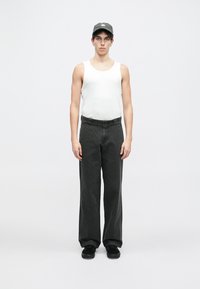 Czarne spodnie o szerokich nogawkach, biały top na ramiączkach i ciemna czapka. Spodnie mają luźny krój, gładką fakturę i nie mają widocznych wzorów.