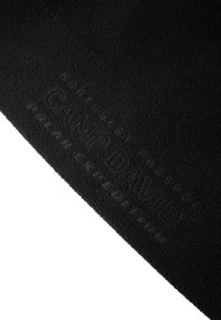 Black fleece fabric featuring embossed text "CAMP DAVID" and "BILAR EXKLUSIVITÄT" for tactile detail and branding. Soft, textured surface.
