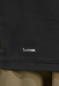 Zwart sportshirt met een zachte textuur. Bevat het "CLIMACOOL" logo in het wit nabij de zoom. De stof lijkt vochtafvoerend en ademend te zijn.