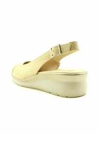 Sandalia slingback beige con un empeine texturizado, diseño de punta abierta, correa ajustable y una suela de cuña acolchada.