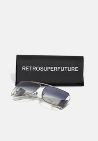 Occhiali da sole con una montatura in metallo argentato, lenti grigie sfumate e dettagli trasparenti, conservati in un astuccio nero contrassegnato "RETROSUPERFUTURE."