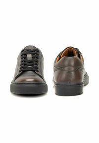 Para brązowych skórzanych butów casualowych z czarnymi sznurowadłami i grubymi gumowymi podeszwami, przedstawiona z przodu i z tyłu na białym tle.