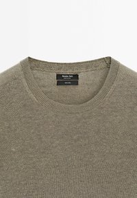 Pull en lin marron clair à col rond côtelé avec étiquette de marque Massimo Dutti visible à l'intérieur de l'encolure.