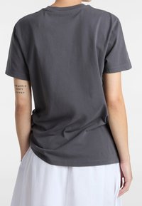 Szara bawełniana koszulka z okrągłym dekoltem i krótkimi rękawami, o luźnym kroju i widocznych detalach szwów.