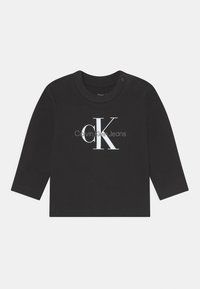 T-shirt noir à manches longues en coton avec un col rond, arborant un logo blanc Calvin Klein Jeans imprimé sur le devant.