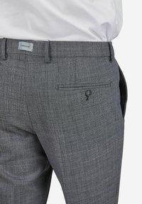 Pantalons à carreaux gris avec une texture lisse, dotés d'une poche arrière avec fermeture à bouton et d'une coupe ajustée.
