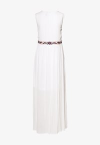Abito maxi bianco con design senza maniche, caratterizzato da una cintura colorata ricamata e un tessuto fluido e trasparente. Chiusura sul retro con bottoni.