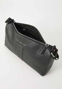 Sac à main en cuir noir avec quincaillerie en argent, fermeture à glissière et logo de marque. Présente une surface texturée et une seule bandoulière réglable.