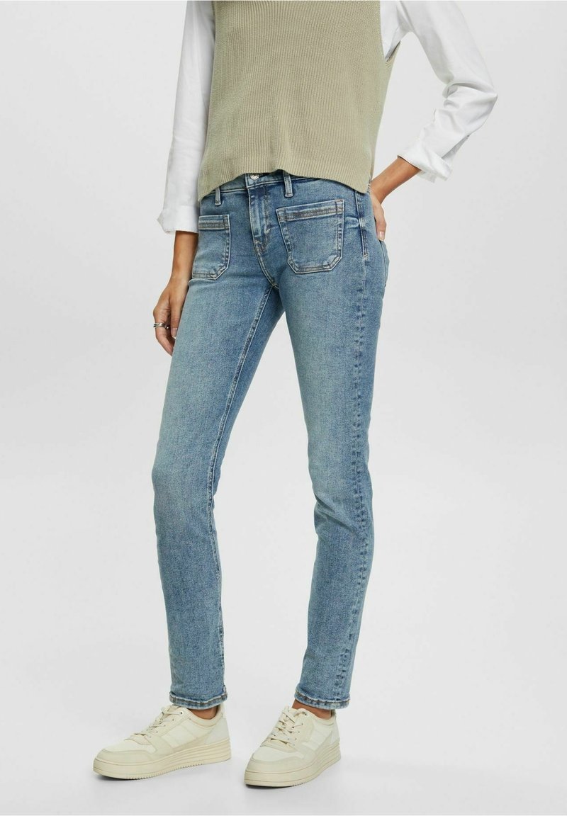 Ljust blå skinny jeans med en urtvättad finish, med en klassisk femficksdesign, i kombination med en grå ärmlös topp och ljusa sneakers.