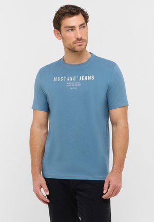 Short-sleeve blue t-shirt made from soft fabric, featuring a round neck and white printed branding on the front. Plain design, casual fit.