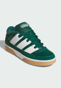 Grön och vit sneaker med en slät läderöverdel, perforerat tåparti, tre vita ränder, vadderad krage och sula av gummiar.