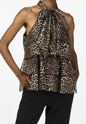 Haut à col licou imprimé léopard avec des volants superposés, présentant un détail nœud au niveau du cou et un tissu léger. Un pantalon noir est porté en dessous.