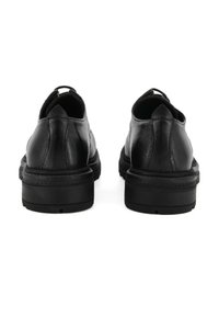 Scarpe in pelle nera con forma arrotondata e tacco basso. Texture liscia con cuciture visibili lungo la suola e l'apertura della caviglia.