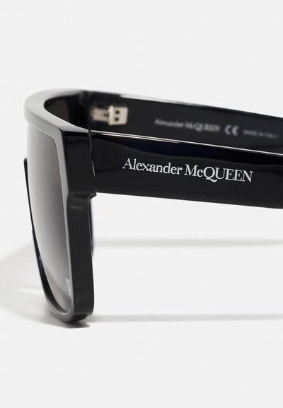 Ochelari de soare negri supradimensionați, cu un design masiv, având o finisare mată și lentile reflectorizante. Logo-ul "Alexander McQueen" gravat pe braț.