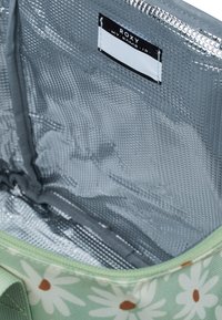 Groene tas met bloemmotief en madeliefjesontwerp; binnenvoering van zilvertextuur materiaal; gelabeld met "Roxy" label.