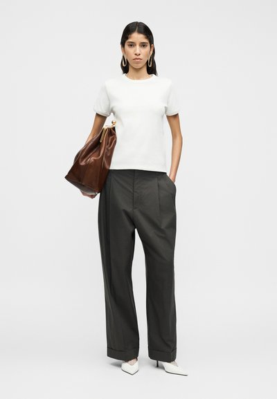 Λευκό κοντομάνικο μπλουζάκι, σκούρο γκρι παντελόνι με ευρύ πόδι και καφέ δερμάτινη τσάντα με χρυσές λεπτομέρειες. Το μοντέλο φορά λευκές γόβες με μυτερή μύτη.