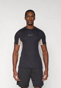 Μαύρο αθλητικό πουκάμισο με ανοιχτό καφέ πλευρικές πινακίδες, κοντά μανίκια και στρογγυλή λαιμόκοψη. Διαθέτει κεντρικό λογότυπο στην περιοχή του στήθους.