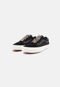 Black suede sneakers with textured, multi-colored woven accents. Features a white rubber sole and signature side stripe design.