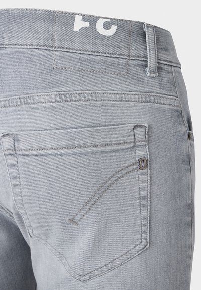 Light gray denim jeans with a fitted design, featuring back pockets with subtle stitching and a logo patch on the waistband.