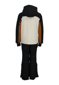 Combinaison de ski d'hiver pour enfants, avec une capuche noire, un corps supérieur crème et des accents marron. Les pantalons sont noirs et les ouvertures des jambes sont renforcées.