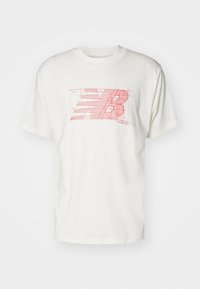 Camiseta de algodón blanca con un gráfico rojo del logo "New Balance" que presenta líneas y círculos geométricos, mangas cortas y cuello redondo.