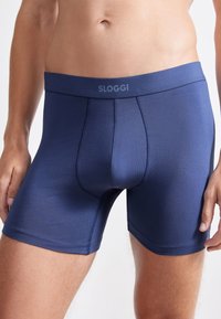 Miestne Sloggi boxerky v tmavomodrej farbe, vyrobené z hladkej látky, s jemným elastickým pásom so svojím logom a priliehavým strihom.