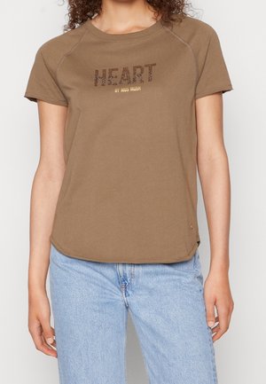 T-shirt en coton marron avec un imprimé texturé et pailleté en forme de "CŒUR" et "by mos mosh" en dessous. Manches courtes, ourlet légèrement arrondi, coupe décontractée.