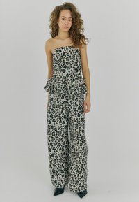 Jumpsuit brez naramnic v leopardjem vzorcu s peplum pasom, izdelan iz lahkotnega materiala. Hlače širokih nog in teksturiran dizajn. Črni akcenti.