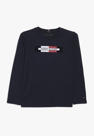 Granatowa koszulka z długim rękawem wykonana z bawełny organicznej, z centralnym wzorem logo w czerwone, białe i czarne paski. Gładka tekstura.