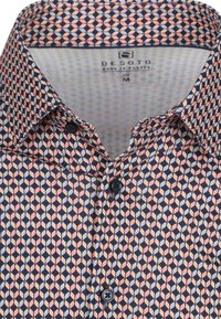 Gestreepte shirt met een marineblauwe basis en een geometrisch bladdesign in tinten perzik en gebroken wit. Knopsluiting met donkere knopen.