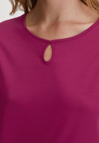 Korte mouw magenta top met een ronde hals en een klein sleufje. Zachte, gladde textuur met een eenvoudig ontwerp.