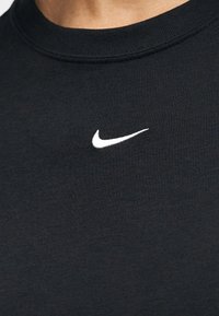 Μαύρο βαμβακερό μπλουζάκι με στρογγυλή λαιμόκοψη και μικρό λευκό κεντημένο λογότυπο Nike στο στήθος. Μαλακή υφή και casual σχεδιασμός.