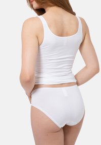 Witte katoenen tanktop met dunne bandjes, gecombineerd met bijpassende witte slips. De stof lijkt zacht en rekbaar, met een gladde textuur.