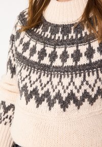 Maglione lavorato a maglia crema e grigio con colletto alto. Presenta motivi geometrici in colori a contrasto e una finitura testurizzata.