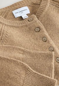 Lammwolle Cardigan in Hellbraun, mit geripptem Kragen und Bündchen, sechs sechseckigen Knöpfen und einem strukturierten Stoff. Etikett mit der Aufschrift "100% LAMMWOLLE."