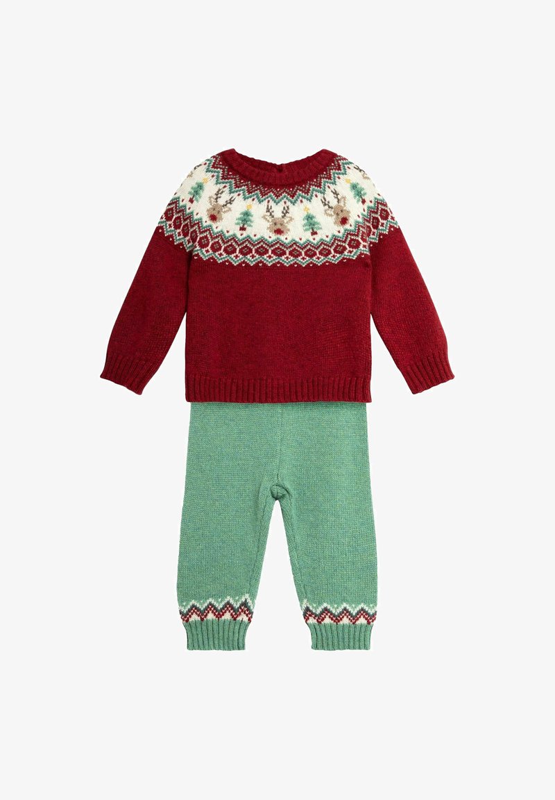 Pull en tricot rouge avec un empiècement festif en crème, vert et rouge ; associé à un pantalon vert texturé avec des poignets à motif.