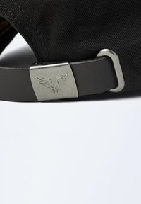 Casquette noire avec un dessus en textile lisse et une sangle noire brillante, dotée d'un fermoir en métal argenté avec des détails de logo gravés.