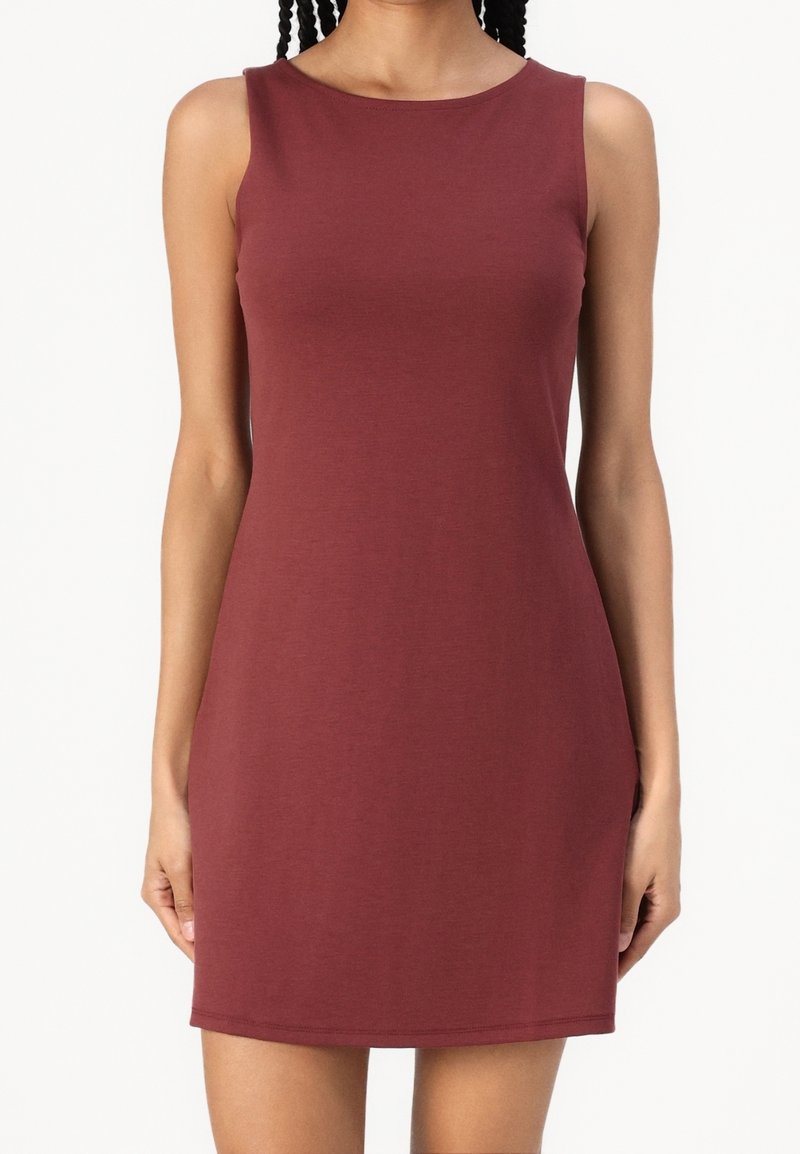 Robe bordeaux sans manches, longueur genou, portée par une personne aux cheveux tressés, debout sur un fond blanc uni.