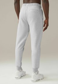 Graue Jogginghosen aus strukturiertem Stoff, mit elastischem Bund und gerippten Bündchen; beinhaltet ein einzelnes Detail in Form einer Rückentasche.