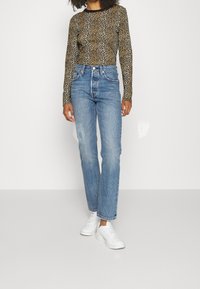 Leopardmönstrad långärmad topp och högmidjade ljusblå jeans. Jeansen har rak passform. Vita sneakers fulländar outfiten.