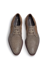 Chaussures en cuir marron avec une surface texturée, présentant un motif tacheté. Accentues par un talon en daim marron lisse et des lacets beiges.