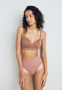Bralette marron sans coutures avec bretelles ajustables et décolleté en V, associé à une culotte taille haute assortie. Texture lisse, design minimaliste.