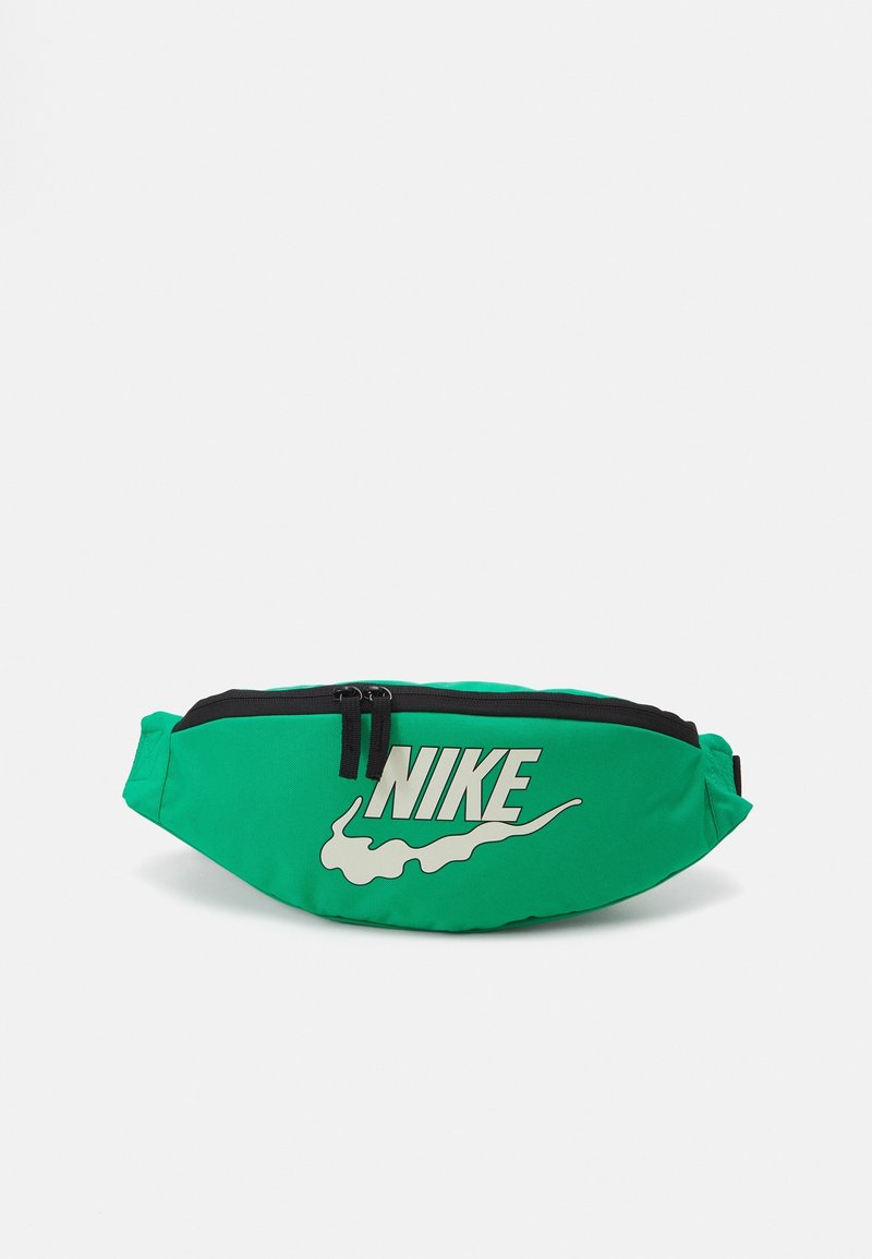 Green Nike fanny pack features a large white logo, black zipper closure, and a smooth textured fabric. Compact, curved shape with adjustable strap.