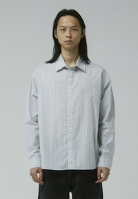 Button-up shirt in light gray with vertical white stripes. Features a classic collar, long sleeves, and a straight-cut hem.