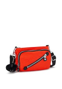 Borsa a tracolla rossa in nylon con accenti neri, caratterizzata da una tasca con zip diagonale, accessori in argento e un dettaglio pom-pom come portachiavi.