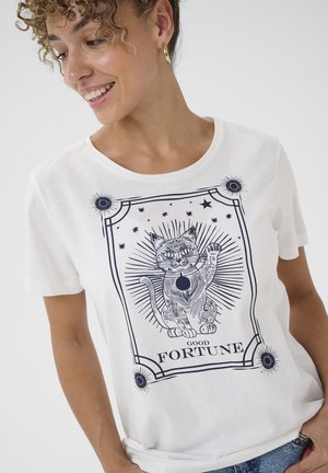 Biała bawełniana koszulka z niebieskim nadrukiem przedstawiającym ozdobionego kota z podniesioną łapą, otoczonego gwiazdami i ozdobnymi promieniami.