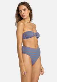 Completo bikini con top senza spalline e nodo e slip a vita alta. Realizzato in materiale a coste con righe blu e arancioni.