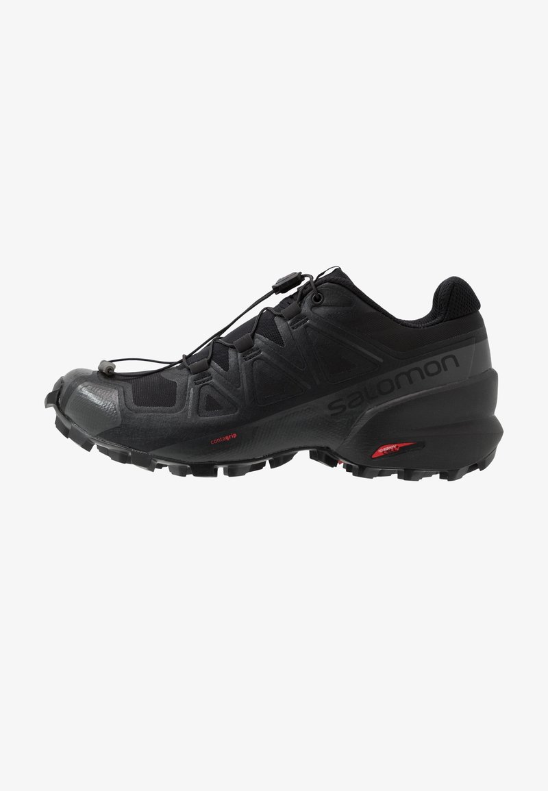 Chaussure de trail noire avec semelle robuste, système de laçage rapide et nom de marque "Salomon" sur le côté.
